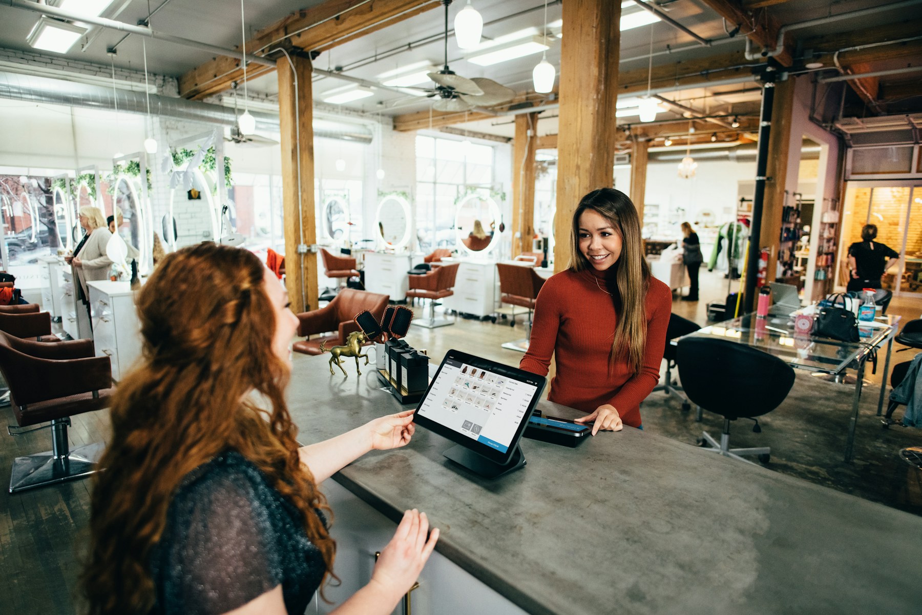 Small business team helping a customer at a salon checkout counter